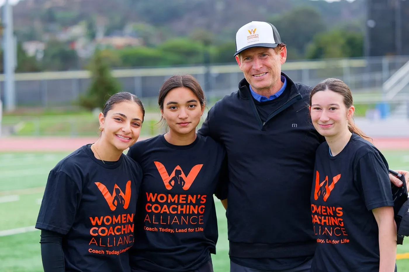 Elevate co-founder Steve Young with three young women coaches in Women’s Coaching Alliance shirts